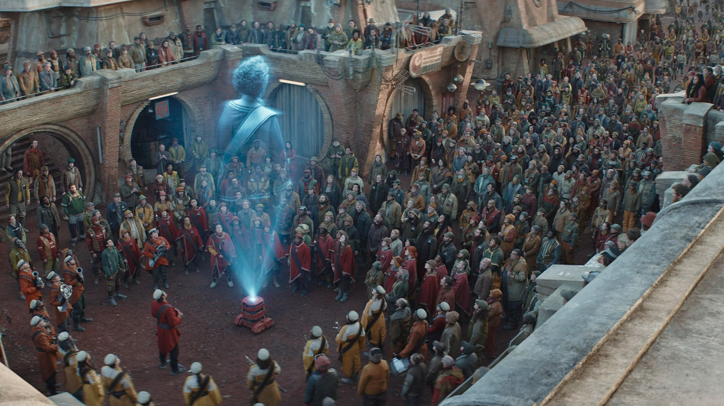 A screen shot from the TV series Andor showing the scene from Marva's funeral where the whole town listens to her speech