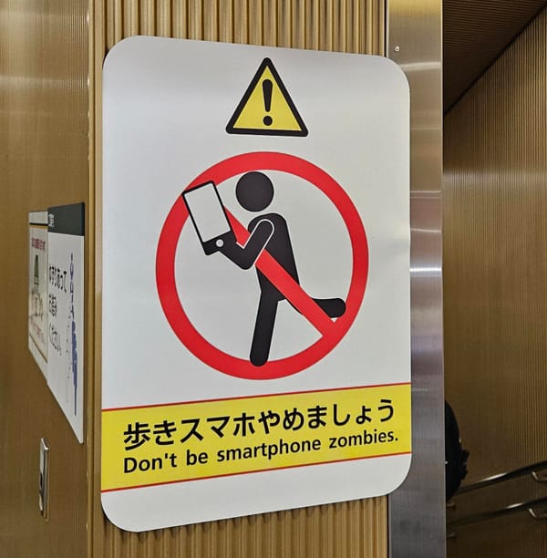 Sign in a Japanese subway station saying "Don't be smartphone zombies"